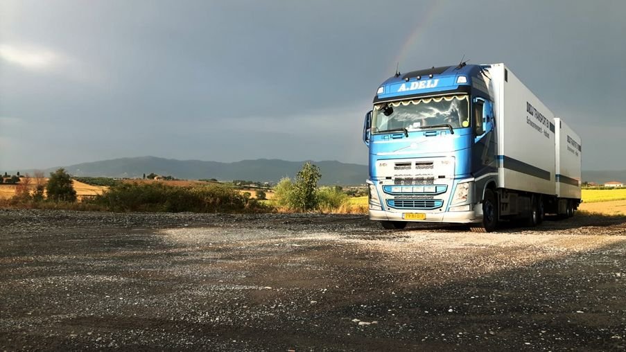 Vrachtwagen van Deij Transport op een terrein onder een donkere lucht